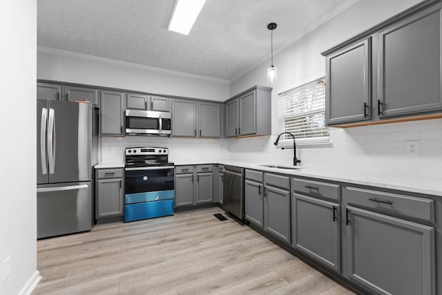 kitchen with stainless steel appliances, gray cabinets, a sink, and light wood-type flooring