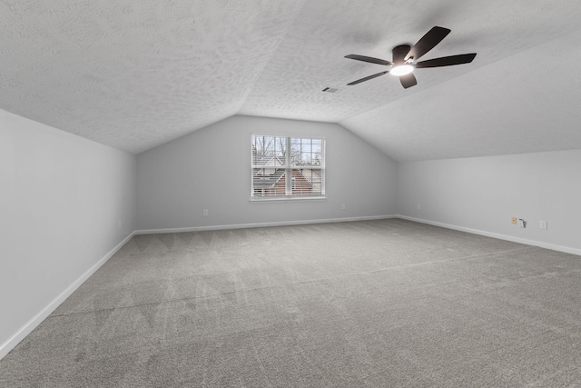 additional living space with a textured ceiling, visible vents, baseboards, lofted ceiling, and carpet flooring