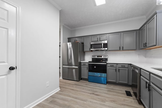 kitchen with decorative backsplash, light wood-type flooring, gray cabinetry, ornamental molding, and stainless steel appliances