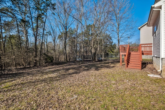 view of yard featuring a deck, fence, and stairs