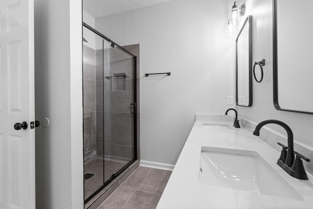 bathroom featuring double vanity, a textured ceiling, a shower stall, and a sink