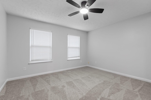 spare room with a ceiling fan, baseboards, carpet, and a textured ceiling