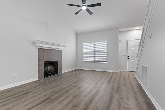unfurnished living room with visible vents, wood finished floors, a fireplace, ceiling fan, and high vaulted ceiling
