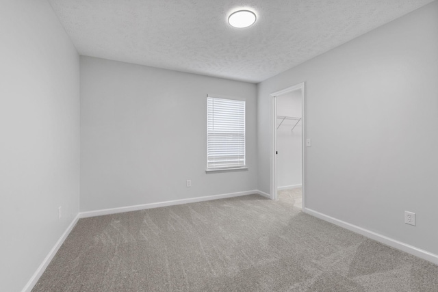 empty room featuring carpet flooring, a textured ceiling, and baseboards