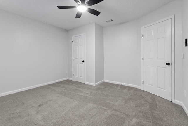 carpeted spare room featuring a ceiling fan, baseboards, and visible vents