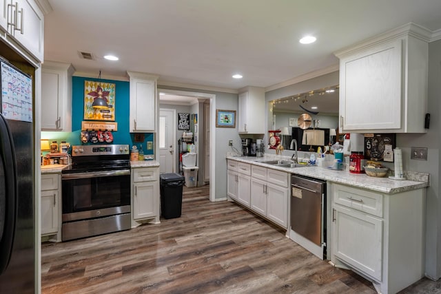 kitchen with visible vents, ornamental molding, wood finished floors, a sink, and appliances with stainless steel finishes