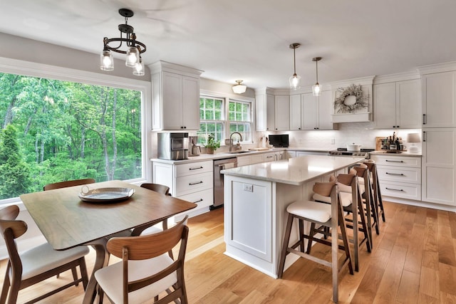 kitchen featuring light wood-style floors, stainless steel dishwasher, a kitchen island, and white cabinets