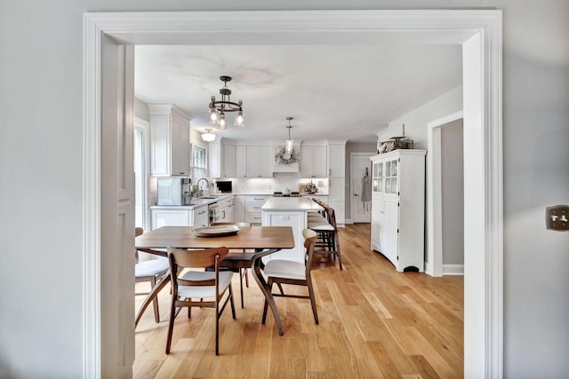 dining room with an inviting chandelier, baseboards, and light wood-type flooring