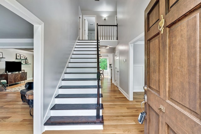 stairs with a towering ceiling, wood finished floors, and baseboards