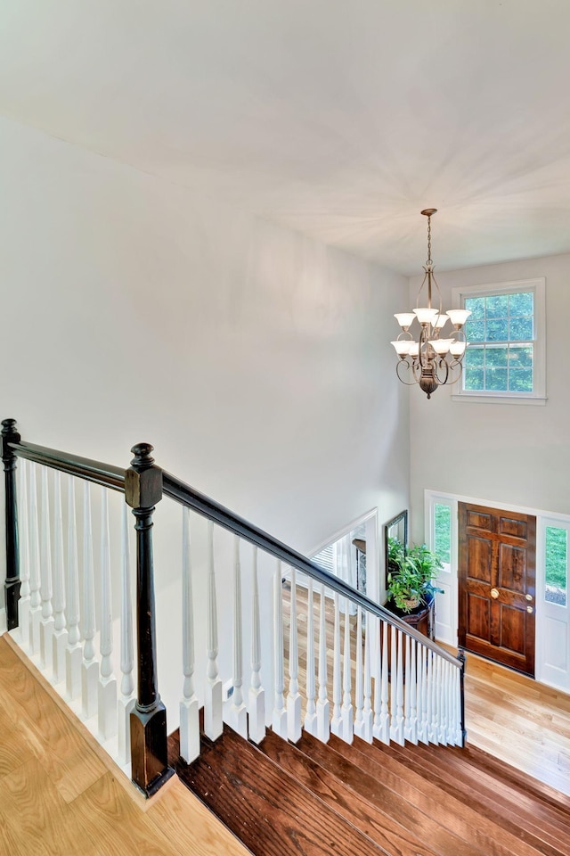 staircase with a notable chandelier and wood finished floors