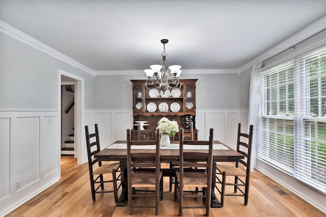 dining room featuring a decorative wall, crown molding, a chandelier, and visible vents