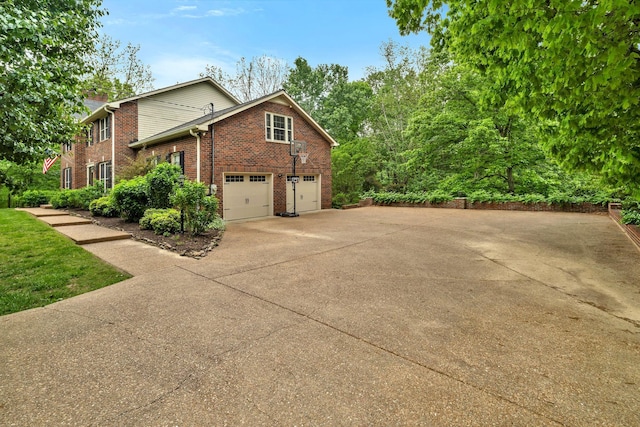 view of side of property featuring concrete driveway, an attached garage, and brick siding