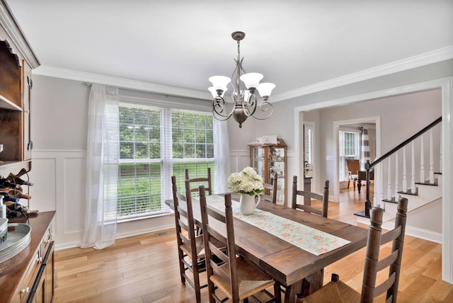 dining area with an inviting chandelier, plenty of natural light, a decorative wall, and crown molding