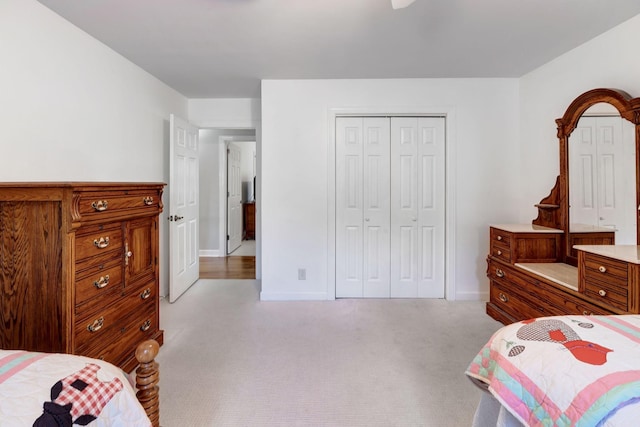 bedroom with light carpet, a closet, and baseboards