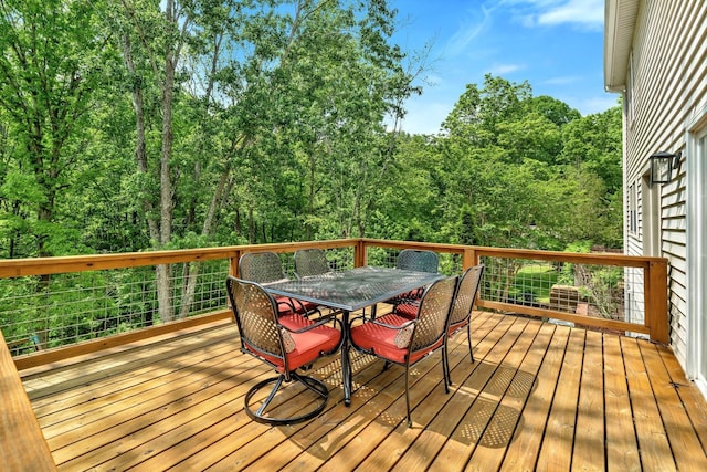 wooden deck featuring outdoor dining area and a forest view