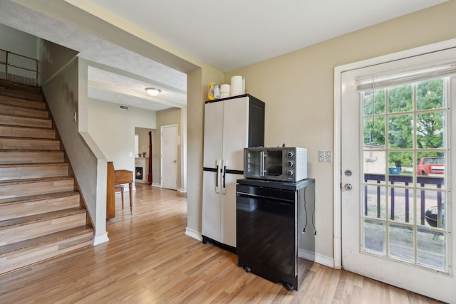 kitchen featuring visible vents, freestanding refrigerator, refrigerator, baseboards, and light wood-style flooring