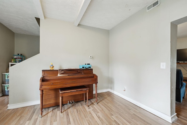 living area with baseboards, a textured ceiling, wood finished floors, and visible vents