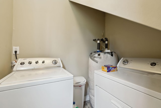 clothes washing area with separate washer and dryer, laundry area, and water heater