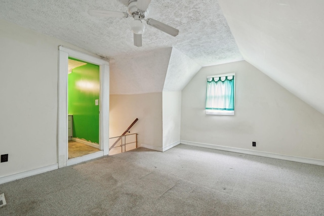 additional living space featuring carpet flooring, a textured ceiling, vaulted ceiling, and visible vents