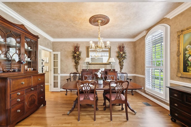 dining space featuring a chandelier, ornamental molding, visible vents, and light wood-type flooring