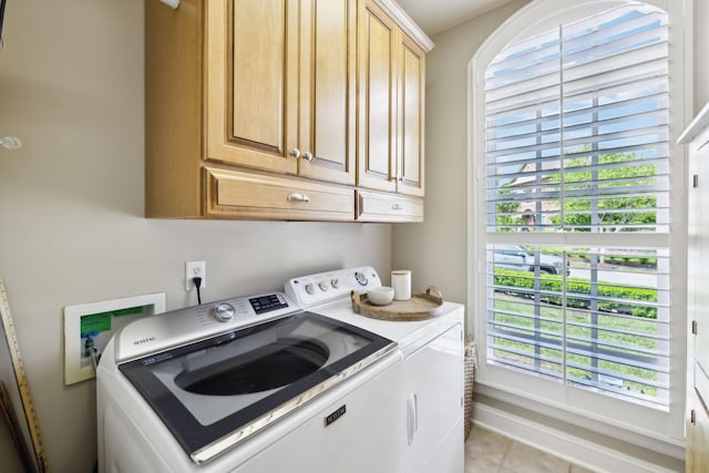 clothes washing area featuring washer and dryer, light tile patterned flooring, plenty of natural light, and cabinet space