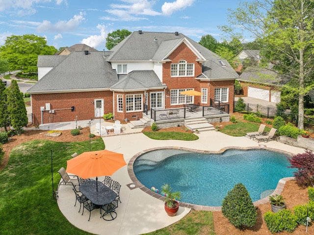 back of property featuring a wooden deck, a patio area, and brick siding