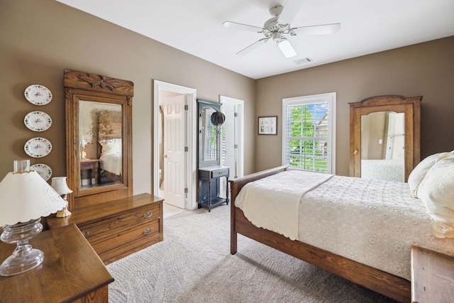 bedroom with connected bathroom, light colored carpet, a ceiling fan, and visible vents