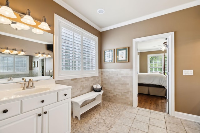 full bathroom with crown molding, wainscoting, vanity, tile patterned floors, and tile walls