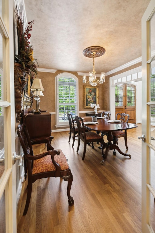 dining room with crown molding, wood finished floors, and a notable chandelier