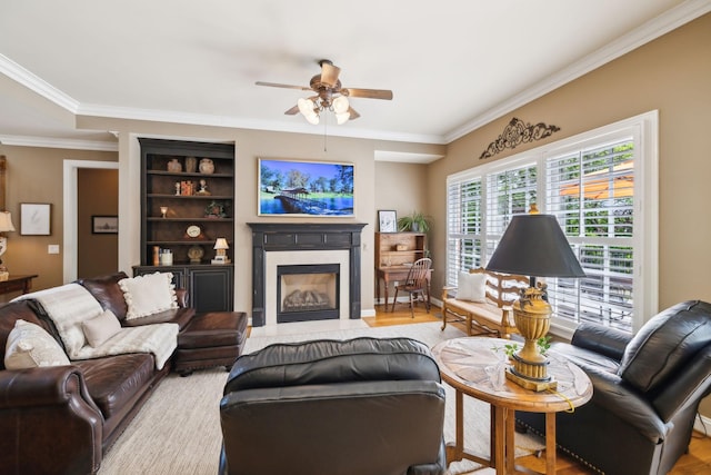 living room featuring crown molding, ceiling fan, a fireplace with flush hearth, and wood finished floors
