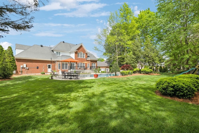 back of house with a patio, a lawn, an outdoor pool, and brick siding