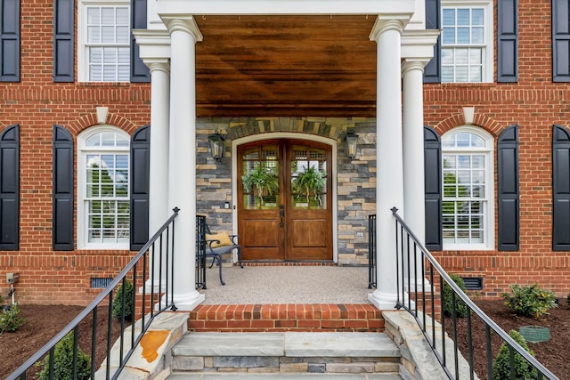 entrance to property with stone siding, french doors, brick siding, crawl space, and a porch