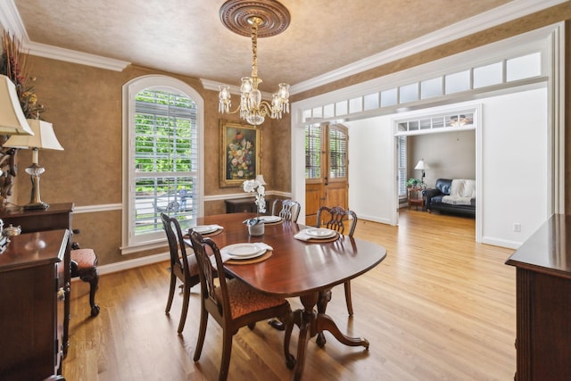 dining room with baseboards, a notable chandelier, ornamental molding, and light wood finished floors