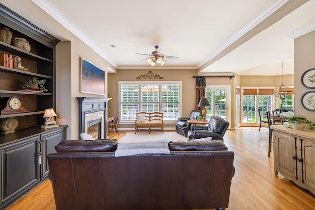 living area with a glass covered fireplace, a ceiling fan, light wood-type flooring, and a healthy amount of sunlight