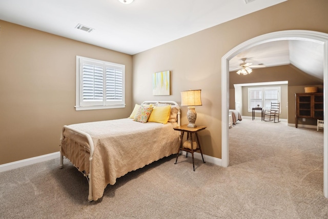 carpeted bedroom with baseboards, lofted ceiling, arched walkways, and visible vents