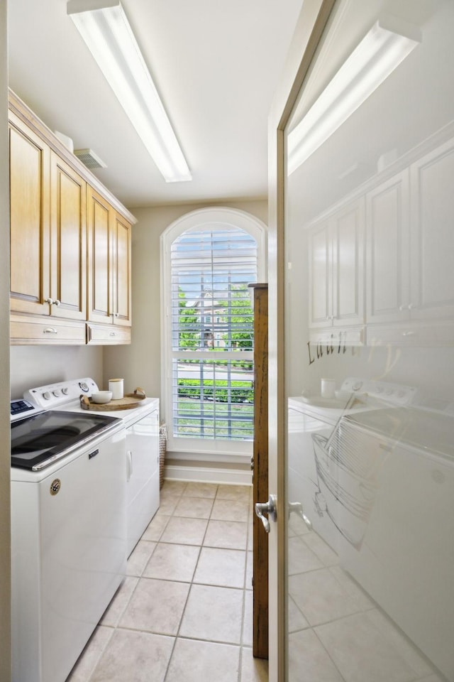 laundry area with baseboards, cabinet space, independent washer and dryer, and light tile patterned floors