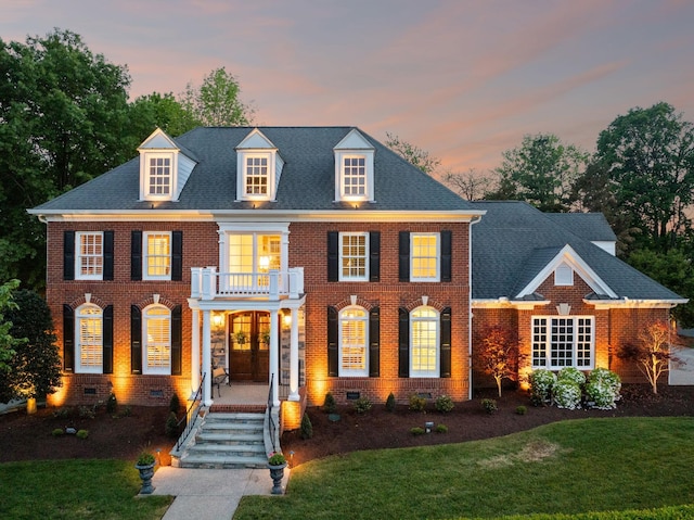georgian-style home with a lawn, crawl space, a balcony, and brick siding