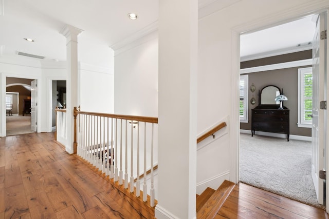 hall featuring crown molding, visible vents, ornate columns, hardwood / wood-style flooring, and an upstairs landing