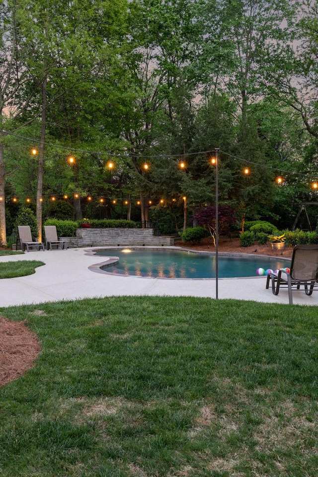 outdoor pool with a lawn and a patio area