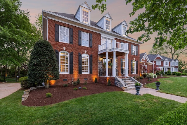 colonial house featuring brick siding, crawl space, a front lawn, and a balcony