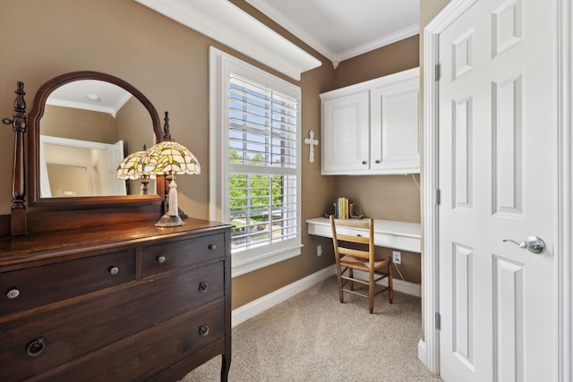 office area with baseboards, ornamental molding, built in desk, and light carpet