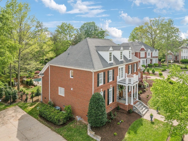 view of property exterior featuring brick siding, fence, a balcony, and crawl space