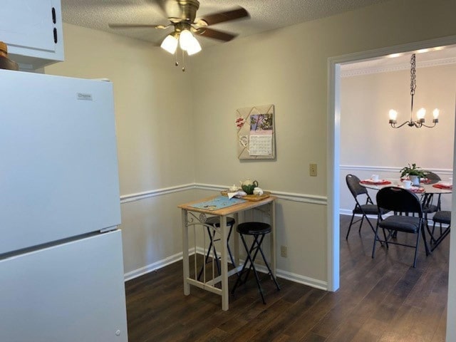 dining area with baseboards, a textured ceiling, wood finished floors, and ceiling fan with notable chandelier