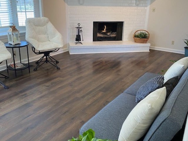 living area with baseboards, a fireplace, and wood finished floors