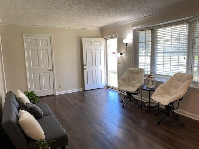 sitting room with baseboards, ornamental molding, a textured ceiling, and dark wood-style flooring