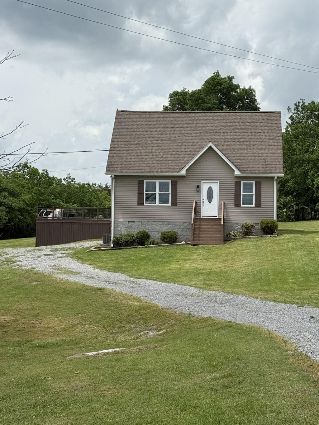 view of front of property with a shingled roof, a front lawn, and gravel driveway