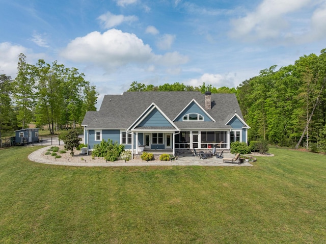 back of property featuring a patio, a lawn, a chimney, and a sunroom