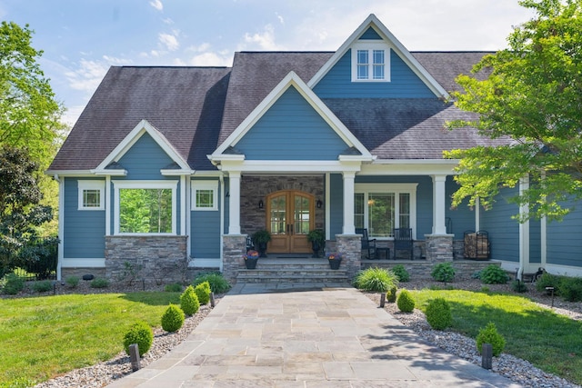 craftsman-style home featuring a front lawn, roof with shingles, french doors, and covered porch