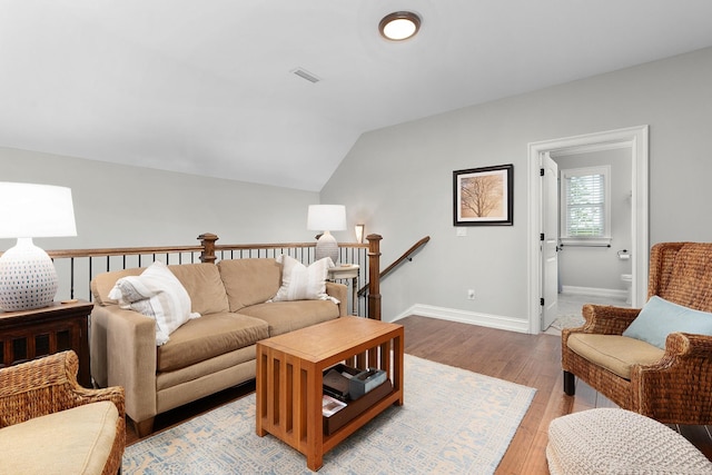 living room with baseboards, vaulted ceiling, visible vents, and light wood-type flooring