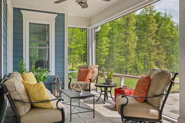 sunroom featuring a forest view, ceiling fan, and an outdoor living space